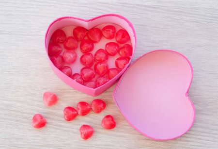 Pink heart-shaped gift box, inside a red heart-shaped candy for Valentine's Day.の写真素材