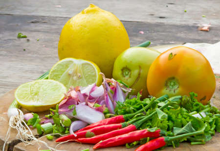 Thai Tom Yam soup herbs and spices. consisting of Kaffir Lime leaves, Galangal, Lemon and Red Chilli on an old wooden tableの写真素材