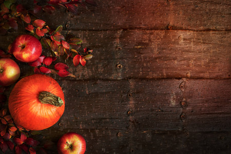 Autumn background with pumpkin, apples and branches with colorful leaves on natural tree bark background. Top view, flat lay, copy space.の写真素材