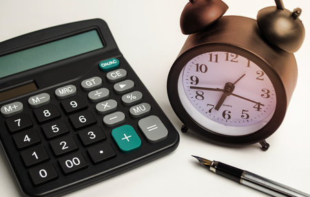 alarm clock with calculator and pen on white backgroundの写真素材
