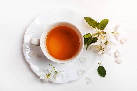 Cup of green tea on figured saucer with white apple tree flowers on white background. View from above. Close up. Horizontal orientation.の写真素材