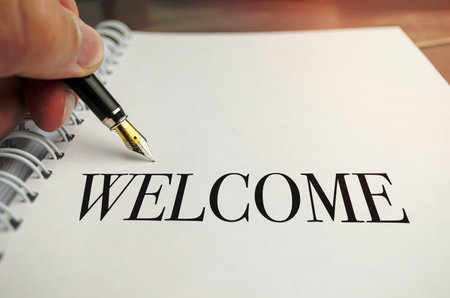 hand writing welcome on white notepad on wooden backgroundの写真素材