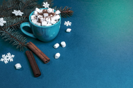 Christmas composition with fir branches with white wooden snowflakes and cup of coffee or cocoa with marshmallows and cinnamon on turquoise. Cozy home holiday. Xmas decorations. Copy space for text.の写真素材