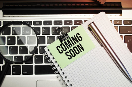 Coming soon words on the paper, magnifier laptop and penの写真素材