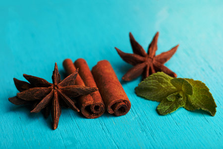 Sticks of cinnamon with one mint and anise stars on wooden turquoise painted background.の写真素材