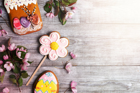 Close-up festive Easter decorations laid out on wooden background. Pink Apple tree branches and...