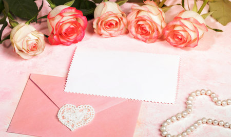 Bouquet of gentle pale pink roses, envelope with lace heart, empty white blank sheet, pearl beads on pink. Festive mock up for Valentine's day, mother's day, wedding, birthday. Holiday card Copy spaceの写真素材