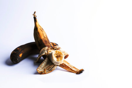 Two overripe blackened ugly bananas on white background with copy space.の写真素材