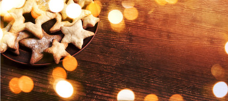 Plate with homemade cookies in form of stars on rustic brown wooden background. Xmas banner with...