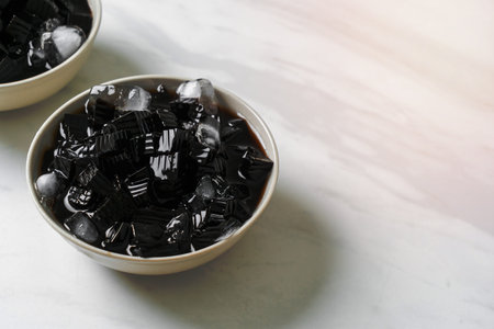 Black grass jelly with ice in bowlの写真素材
