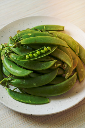 fresh sweet green peas on white plateの写真素材