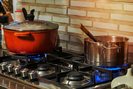 Preparing food in frying pan and casseroles on the gas stove in the kitchen. Home cooking concept.