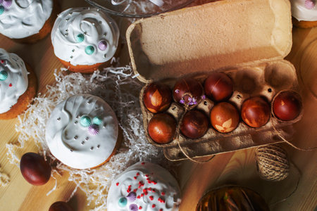 Painted eggs cooked for Easter are in a tray near pies with white icingの写真素材