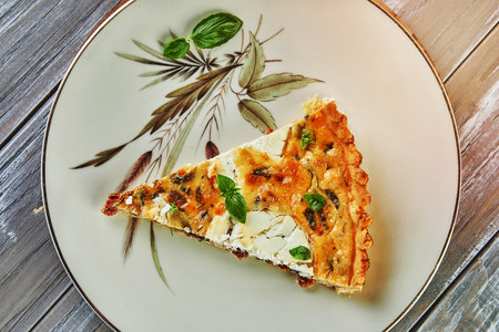 Piece of quiche with goat cheese on plate. French gourmet cuisine.