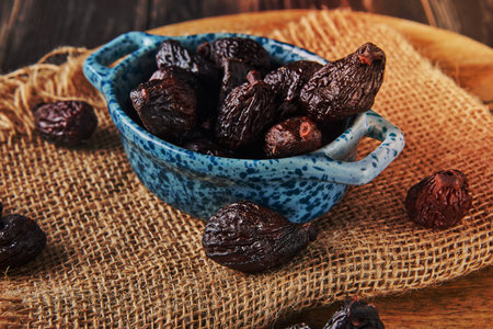 Dried mission figs in glass bowl on burlap and wooden background. Close up