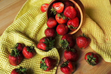 garden berry, red berry, strawberries in a plate, wooden plate, yellow cloth, harvest, summer season, seasonal berries, fruit plateの写真素材