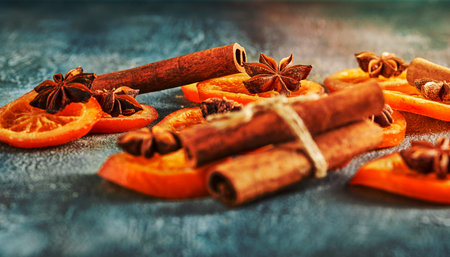 Slices of dried oranges or tangerines with anise and cinnamon, on a blue background. Vegetarianism and healthy eating. Copy space.の写真素材