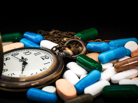 Antique clock on multicolored of drug and capsule is on the black background. Close up. We are against drugs (anti drugs), cure in container for health.Heap of green blue white round capsule pillsの写真素材