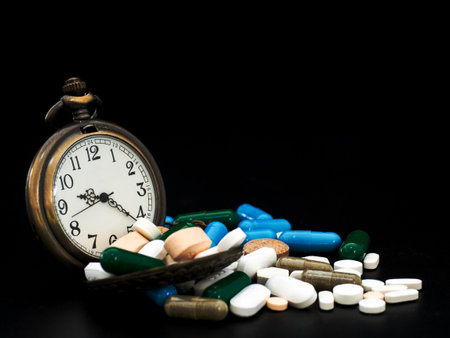 Antique clock on multicolored of drug and capsule is on the black background. Close up. We are...