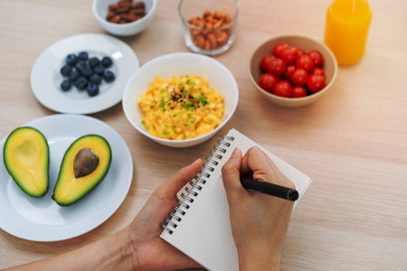 Diet, Dieting hand of asian young woman, girl write diet plan nutrition on table is different food ingredients in the green. Nutritionist of healthy, nutrition of weight loss, health care people.の写真素材