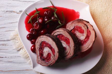 Meat roll stuffed with cherries close-up on a plate and sauce. horizontal view from aboveの写真素材
