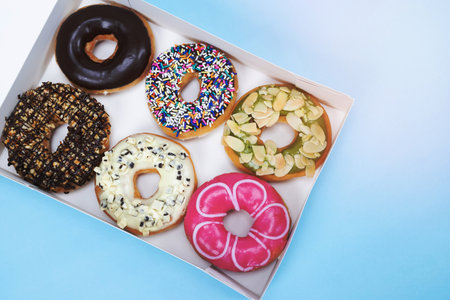 assorted donuts with chocolate frosting, topping sprinkles donuts Colorful variety and Variety of flavors mix of multi colored sweet donuts with frosted sprinkled on blue background. top viewの写真素材