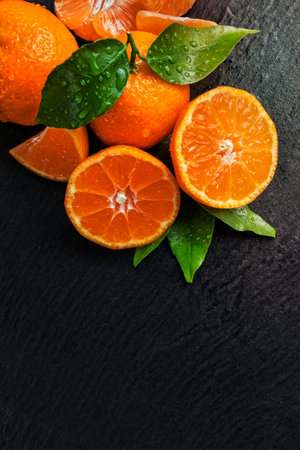 Fresh dewy mandarin placed on black stone, top view. Copyspace for textの写真素材