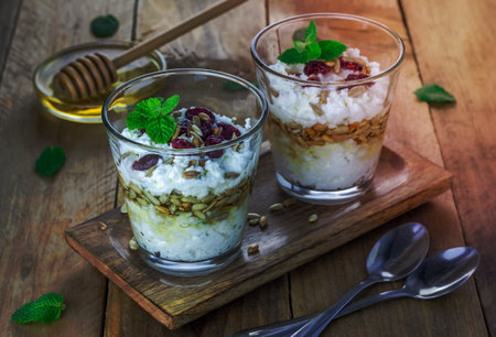 Ricotta cheese dessert with honey, sunflower seeds and mint, garnished with dry cranberriesの写真素材