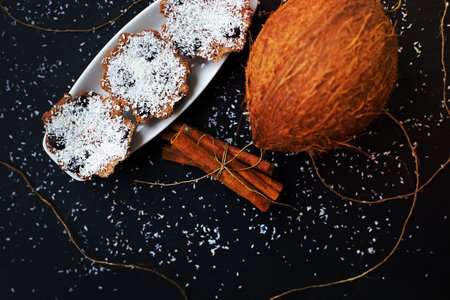 coconut muffins with chocolate and cinnamon on a black background and whole coconutの写真素材