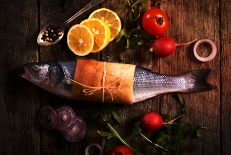 bass fish and vegetables in the pan on wooden backgroundの写真素材