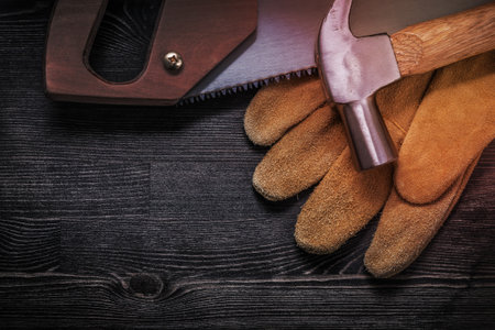 Hand saw claw hammer safety gloves on wooden board.の写真素材