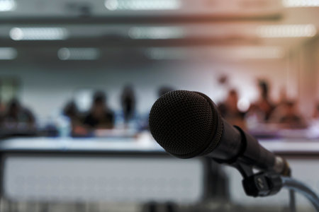 Microphone on the abstract blurred photo of seminar room backgroundの写真素材