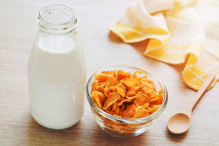 Bowl of cornflake and milk bottle on tableの写真素材