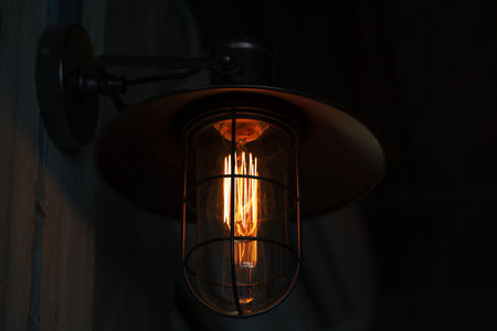 A classic Edison light bulb on old wall background switched on.の写真素材