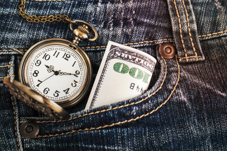 Pocket watch and a dollar bill in blue jeansの写真素材