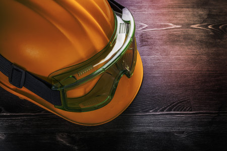 Protective glasses hard hat on wooden board construction concept.