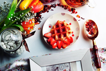 Viennese wafers with strawberry syrup and strawberries in a still life with tulipsの写真素材