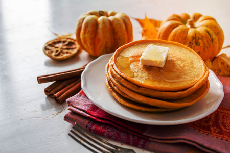 Pumpkin pancakes on white plate with butter and honey, white wood backgroundの写真素材