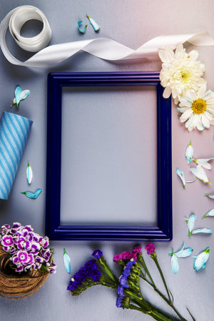 top view of an empty picture frame with purple and pink color statice flowers and chrysanthemum flowers and petals, a ball of rope with turkish carnation on white background with copy spaceの写真素材