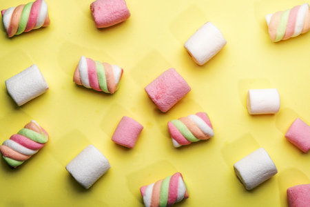top view of colorful marshmallow scattered on yellow backgroundの写真素材