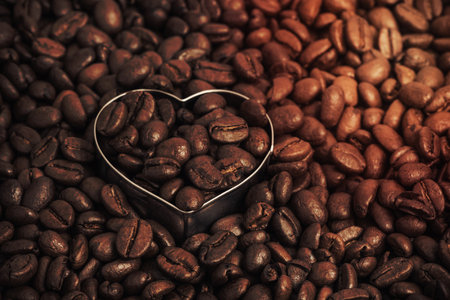 Closeup of dark roasted coffee beans and a heart. Food and drink backdrop showing aromatic and beautiful coffee beans with copy space. Can be used as a conceptual image for breakfast time, having a coffee break or any industry working with food and beverage.の写真素材