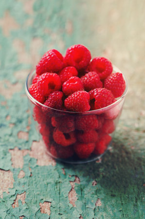 raspberry in a glass bowl on wooden surfaceの写真素材