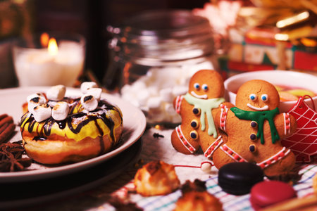 colorful Christmas sweets and hot drinks on the holiday table near the Christmas treeの写真素材