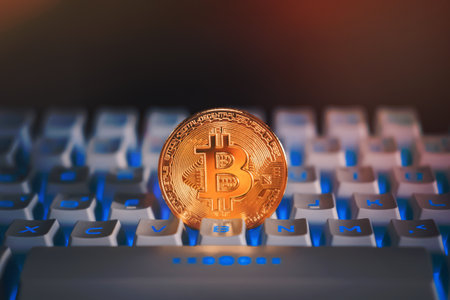 Gold bitcoin on a white keyboard with blue light or RGB keyboard. Cryptocurrency virtual money. Blockchain technology concept.の写真素材
