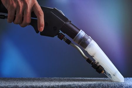 Horizontal shot of washing carpet with hoover close-up on blue background. The hand holds the hoover.の写真素材