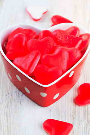 heart-shaped candies in a bowl on wooden surfaceの写真素材