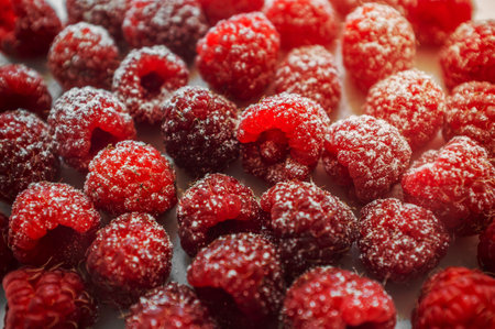 Raspberry berries on a white background. A portion of the ripe berries powdered with icing sugar. A studio photo on a light background.の写真素材