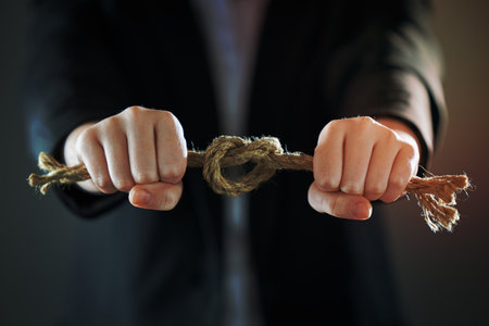 Horizontal shot of businessman's hands tighten the rope knot against background of suit in blur. People and business concept.の写真素材
