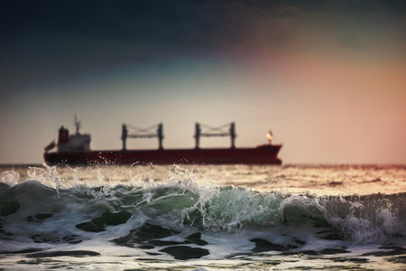 Sun setting at the sea with sailing cargo ship, scenic viewの写真素材