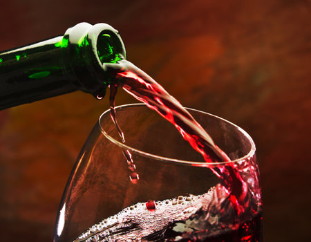 Wine pours into the glass of the bottle on a colored backgroundの写真素材